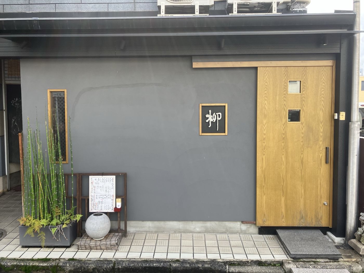 柳の外観。グレーの壁に木の引き戸と「柳」の看板